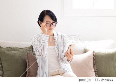 ミドル女性　老眼鏡をかけてスマホを見るミドル女性 112044833