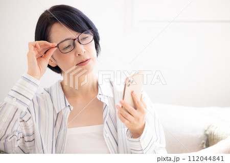 ミドル女性 老眼鏡をかけてスマホを見るミドル女性 ミドル女性 老眼鏡をかけてスマホを見るミドル女性 112044841