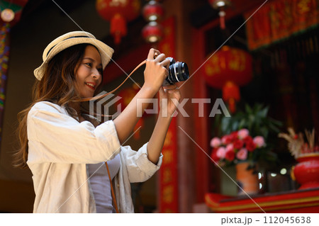 Attractive female tourist taking photo with her camera at Chinatown district in Chiang Mai, Thailand Attractive female tourist taking photo with her camera at Chinatown district in Chiang Mai, Thailand 112045638