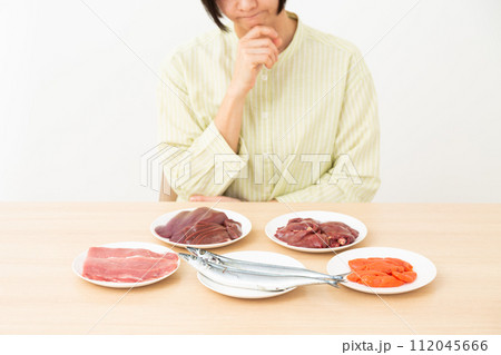 ビタミンB群を多く含む食品を見て悩むミドル女性 112045666