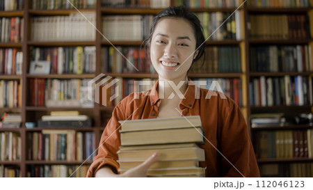 Smiling asian woman holding books at library, medical student doing research Smiling asian woman holding books at library, medical student doing research 112046123