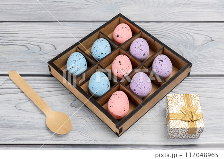 Colorful Easter eggs in a box and a gift box on the wooden background 112048965