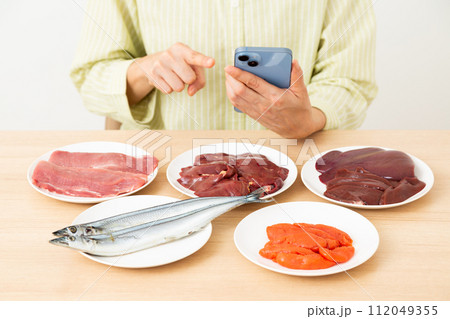 ビタミンB群を多く含む食品とスマホを操作するミドル女性 ビタミンB群を多く含む食品とスマホを操作するミドル女性 112049355
