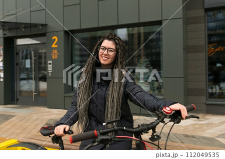 Photo on the street, a young active woman with a dreadlocked hairstyle, dressed in a warm jacket 112049535