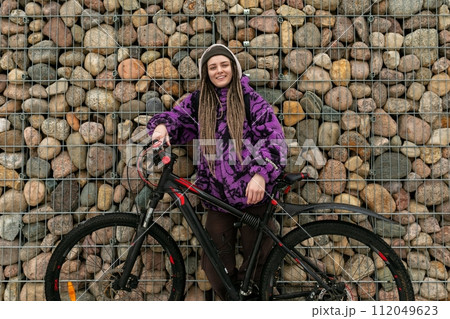 Lifestyle concept. Young woman with piercings and dreadlocks rides a bicycle 112049623