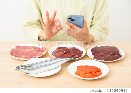 ビタミンB群を多く含む食品とスマホを持って丸サインをするミドル女性 112049912