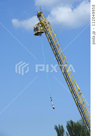 bungee jumping. Young woman jumping from the high rise tower crane. 112049958