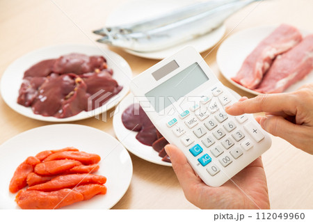 ビタミンB群を多く含む食品と電卓を持つミドル女性 112049960