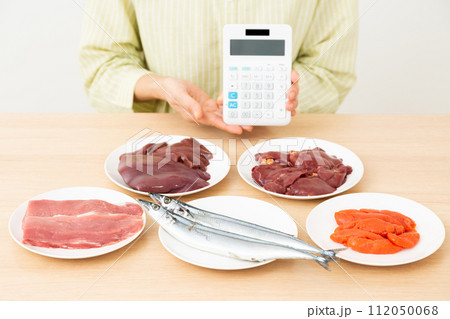 ビタミンB群を多く含む食品と電卓を持つミドル女性 112050068