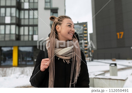 A pretty young woman with dreadlocks dressed in a black coat walks through the city A pretty young woman with dreadlocks dressed in a black coat walks through the city 112050491