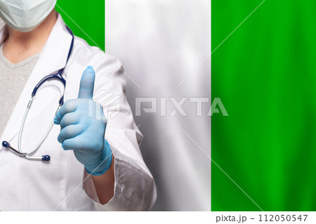 Nigerian doctor's hand showing thumb up positive gesture on flag of Nigerian background 112050547