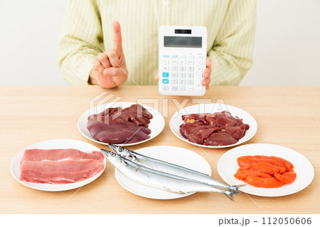 ビタミンB群を多く含む食品と電卓を持って人差し指を立てるミドル女性 112050606