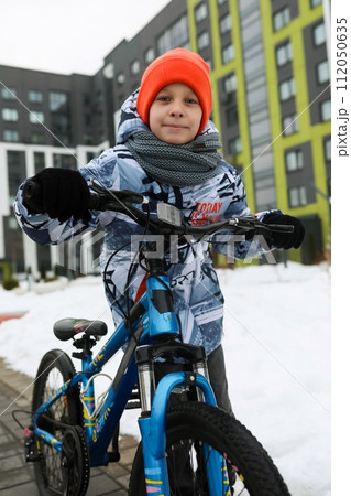 European child riding a bicycle in the yard in winter European child riding a bicycle in the yard in winter 112050635