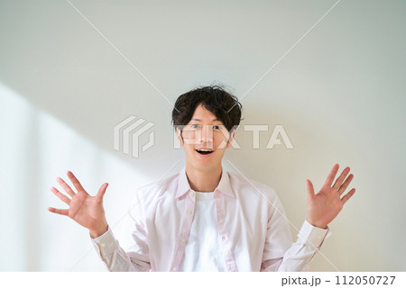 両手を広げて、驚いている若い男性 112050727