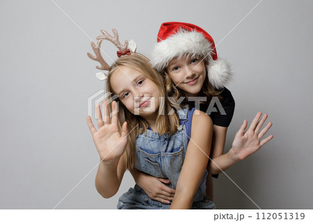 Christmas portrait of happy kid girls best friends hugging on gray background 112051319