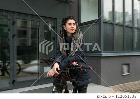 Urban pretty woman with dreadlock hairstyle rides a bicycle Urban pretty woman with dreadlock hairstyle rides a bicycle 112051538