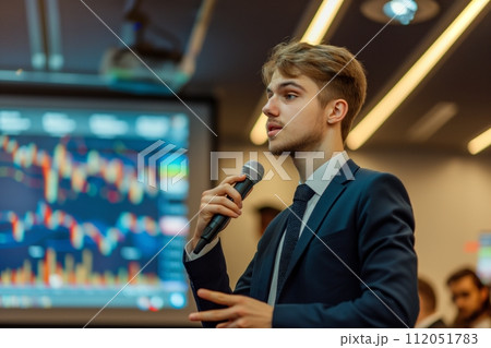 Young entrepreneur explaining concepts against a backdrop of glowing stock market screens 112051783