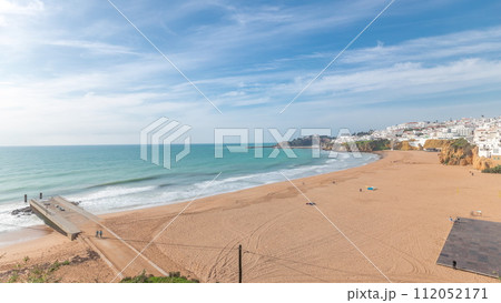 Wide sandy beach and Atlantic ocean in city of Albufeira timelapse. Algarve, Portugal 112052171