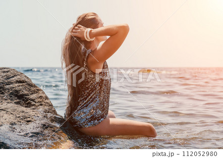 Woman summer travel sea. Happy tourist enjoy taking picture outdoors for memories. Woman traveler posing on the beach at sea surrounded by volcanic mountains, sharing travel adventure journey Woman summer travel sea. Happy tourist enjoy taking picture outdoors for memories. Woman traveler posing on the beach at sea surrounded by volcanic mountains, sharing travel adventure journey 112052980