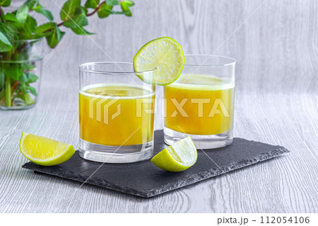 Fresh lime juice in glasses on slate coaster. World Juice Day. Fresh lime juice in glasses on slate coaster. World Juice Day. 112054106