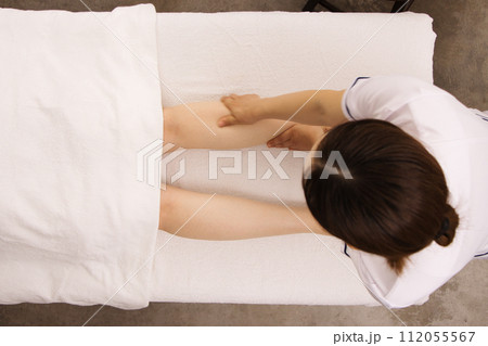 エステティシャンにフットマッサージを受ける女性 112055567