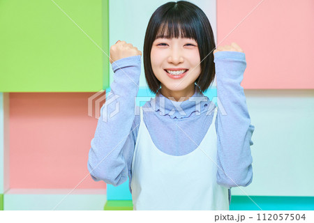 ガッツポーズをする若い女性とカラフルな背景 ガッツポーズをする若い女性とカラフルな背景 112057504