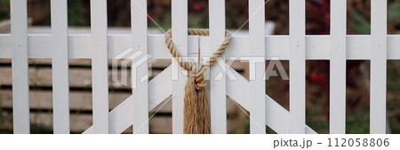 Banner rope knot on white picket fence. Banner rope knot on white picket fence. 112058806