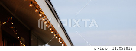 Banner roof of a wooden one-story house with garland 112058815