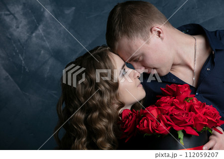 Beautiful young couple .Hugs, kisses and enjoys spending time together, celebrating Valentines Day with red roses. Beautiful young couple .Hugs, kisses and enjoys spending time together, celebrating Valentines Day with red roses. 112059207