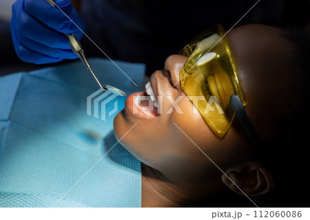 Woman in protective glasses visiting dentistry clinic for teeth treatment Woman in protective glasses visiting dentistry clinic for teeth treatment 112060086
