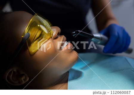 Multicultural female patient opens mouth while sitting in dentist chair in clinic Multicultural female patient opens mouth while sitting in dentist chair in clinic 112060087