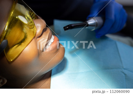 Multicultural female patient opens mouth while sitting in dentist chair in clinic 112060090