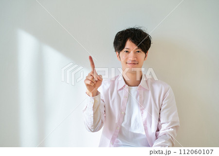 人差し指を上げるポーズをする若い男性 112060107