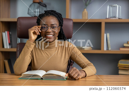 Smiling woman reading business book of entrepreneurship gaining insights for her business Smiling woman reading business book of entrepreneurship gaining insights for her business 112060374