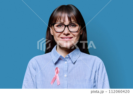 Middle-aged woman with pink ribbon symbolizing International Breast Cancer Day 112060420