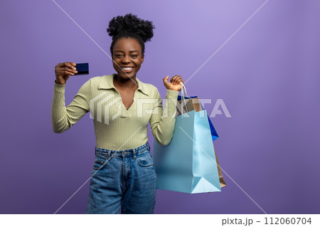 Pretty dark-skinned woman with credit card and shopping bags 112060704