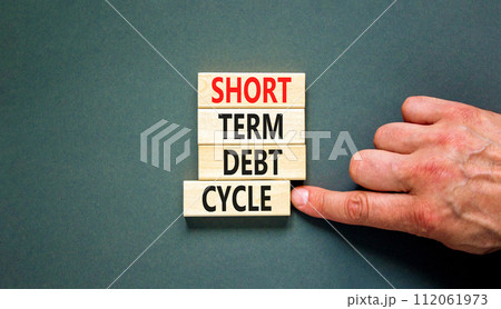 Short term debt cycle symbol. Concept words Short term debt cycle on beautiful wooden block. Beautiful grey table grey background. Businessman hand. Business Short term debt cycle concept. Copy space. 112061973