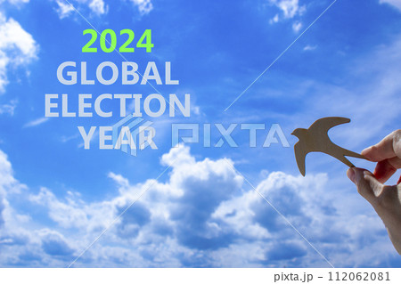 2024 global election year symbol. Concept words 2024 global election year. Beautiful blue sky cloud background. Voter hand with wooden bird. Business 2024 global election year concept. Copy space 2024 global election year symbol. Concept words 2024 global election year. Beautiful blue sky cloud background. Voter hand with wooden bird. Business 2024 global election year concept. Copy space 112062081