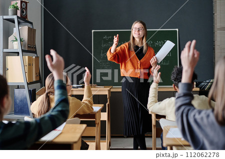 Selective focus shot of children raising their hands willing to answer teachers question during music lesson Selective focus shot of children raising their hands willing to answer teachers question during music lesson 112062278