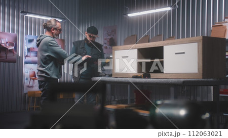 Male designer with digital tablet discusses making TV stand with colleague Male designer with digital tablet discusses making TV stand with colleague 112063021