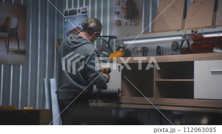 Professional male craftsman makes and assembles TV stand 112063085