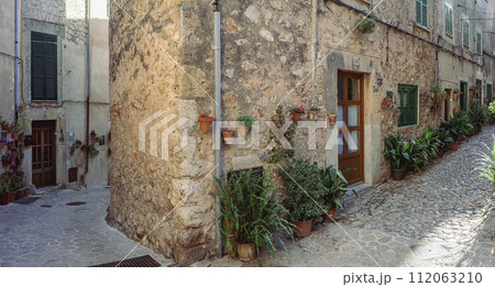 Charming Cobblestone Street with Rustic Potted Plants in Mediterranean Village Charming Cobblestone Street with Rustic Potted Plants in Mediterranean Village 112063210