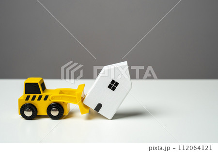 A bulldozer demolishes a house. Toy figures. Territory clearing service. The bulldozer intends to demolish the house. Making way for future developments. 112064121