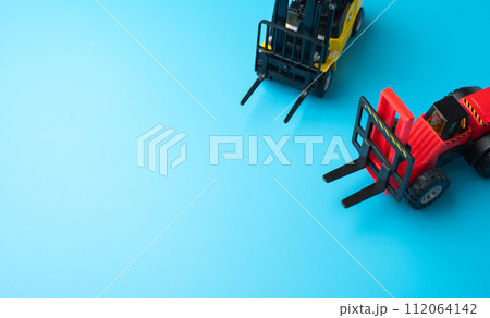 Forklifts and space for text on a blue background. Efficient logistics and distribution systems. Management of warehousing and shipping of orders and goods. 112064142