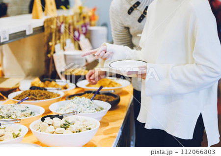 ビュッフェスタイルのレストランで料理を選ぶカップル 112066803