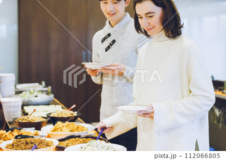 ビュッフェスタイルのレストランで料理を選ぶカップル 112066805