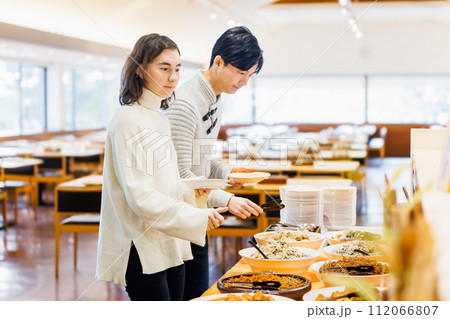 ビュッフェスタイルのレストランで料理を選ぶカップル 112066807