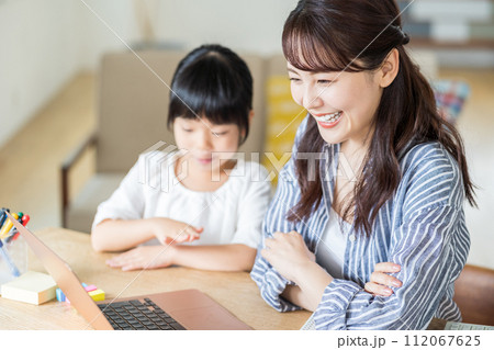 テレワークをする母親と寄り添う女の子。 テレワークをする母親と寄り添う女の子。 112067625