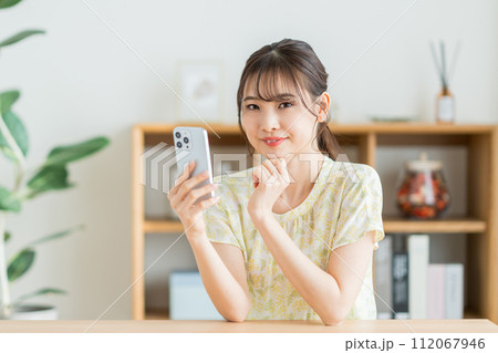 リビングでスマホを操作する女性。 リビングでスマホを操作する女性。 112067946