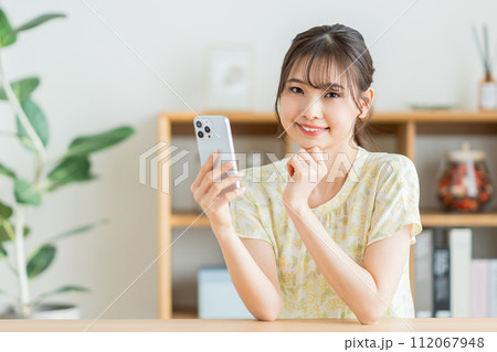 リビングでスマホを操作する女性。 112067948
